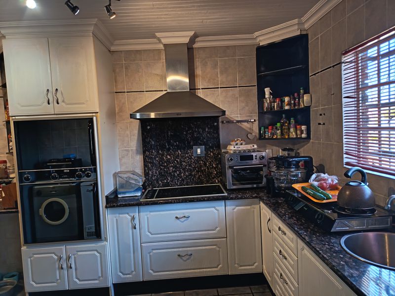 A functional kitchen featuring built-in oven, extractor fan, granite countertops, and tiled backsplash with classic cabinetry.