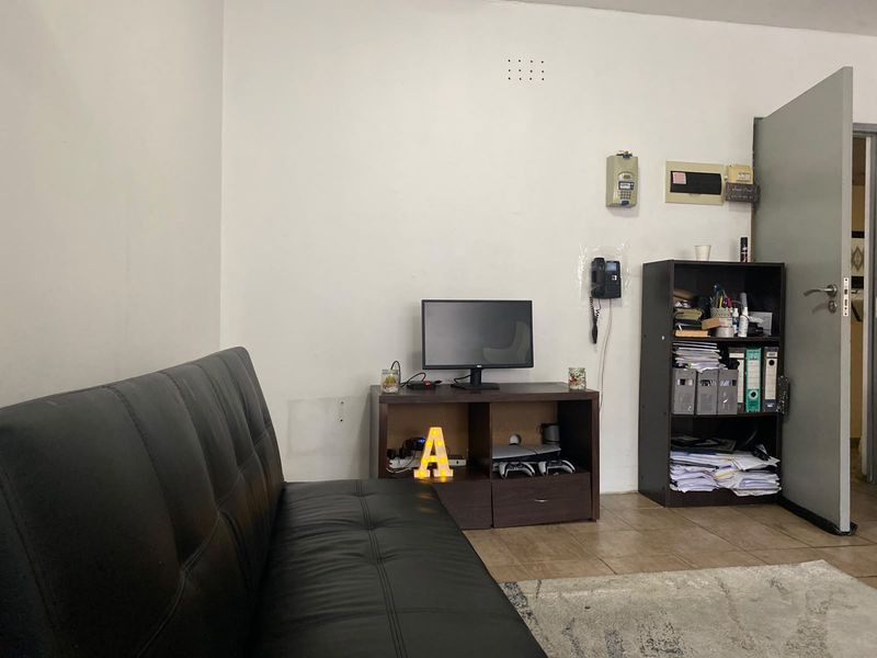 A living room area featuring tiled flooring and an integrated intercom system, requiring cosmetic updates to the wall finishes.