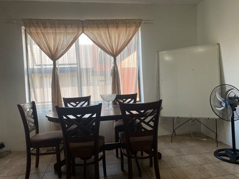 A dining area featuring tiled flooring and a large window, providing natural light to the space.