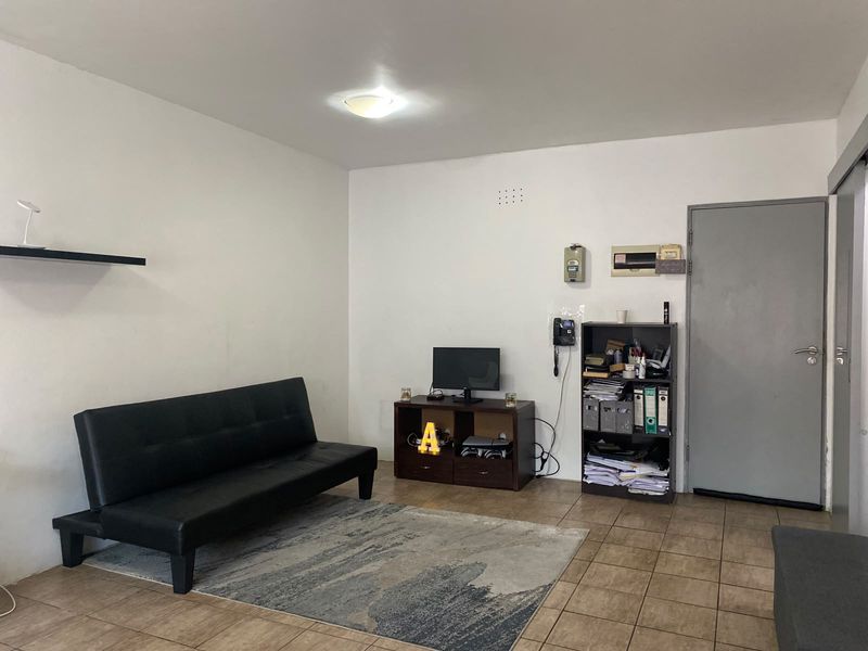 A functional living room featuring tiled flooring, an intercom system, and a neutral wall finish, providing a blank canvas for interior design updates.