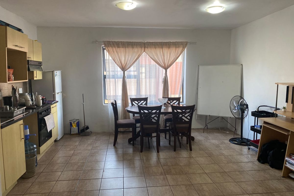 Open-plan living and kitchen area featuring tiled flooring, functional cabinetry, and built-in cooking appliances, offering a versatile space for dining and daily living.