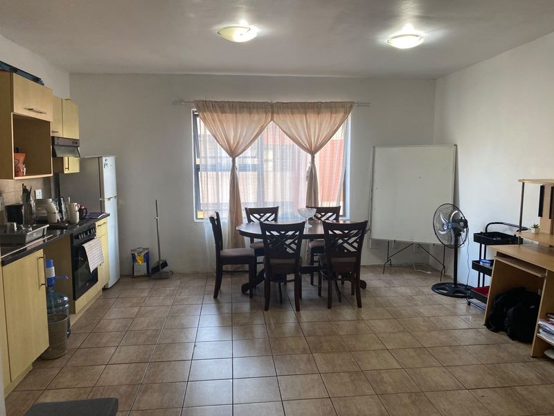 Open-plan living and kitchen area featuring tiled flooring, functional cabinetry, and built-in cooking appliances, offering a versatile space for dining and daily living.