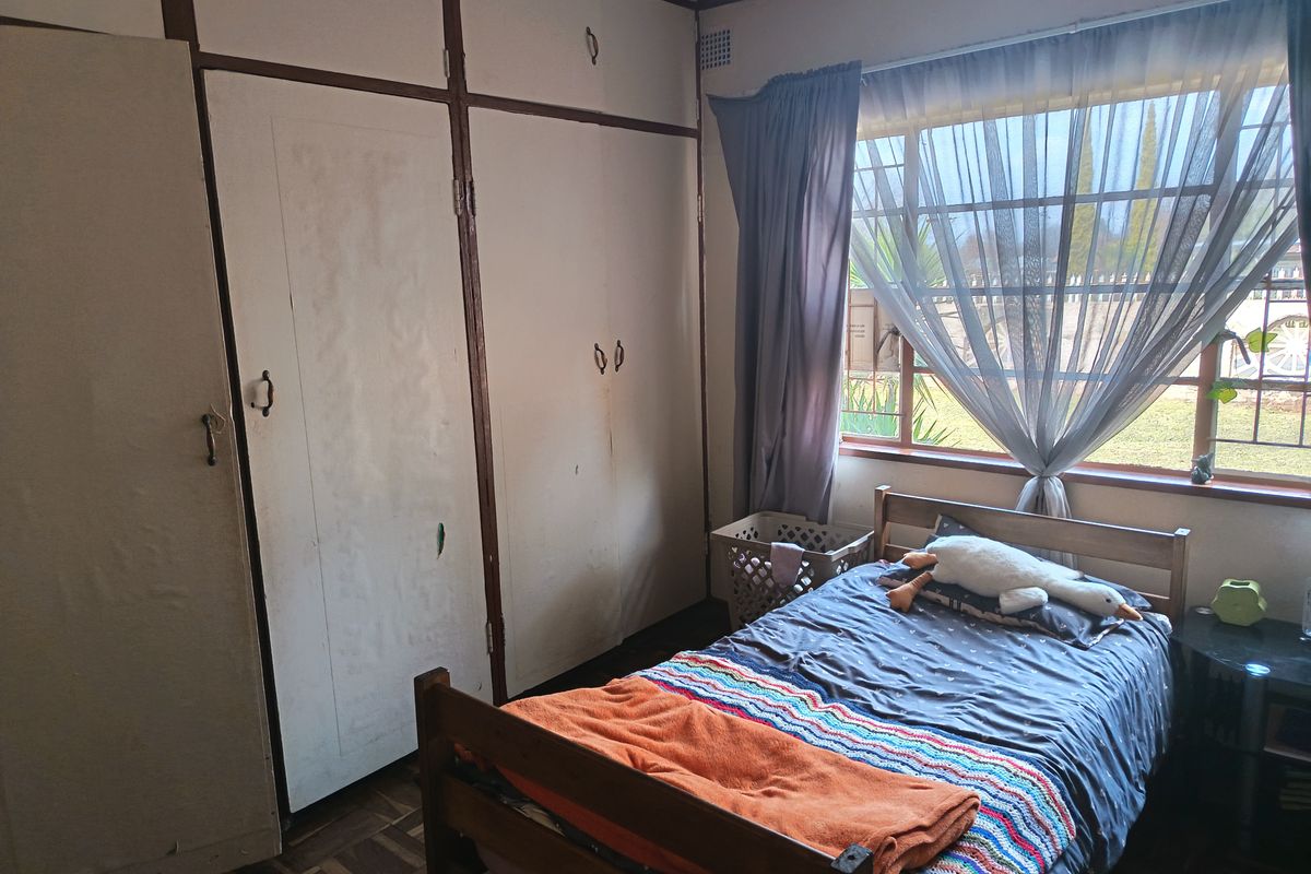 A bedroom featuring original parquet flooring and extensive built-in cupboard storage, offering a functional space with potential for cosmetic updates.