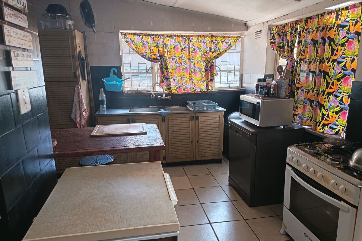 A functional kitchen featuring tiled flooring, built-in cabinetry, and a gas stove, offering potential for modernization and aesthetic updates.