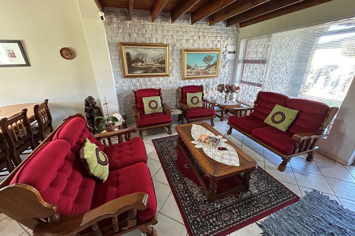 A cozy living room featuring a painted brick accent wall, exposed timber beam ceiling, and tiled flooring, offering a warm and traditional atmosphere.