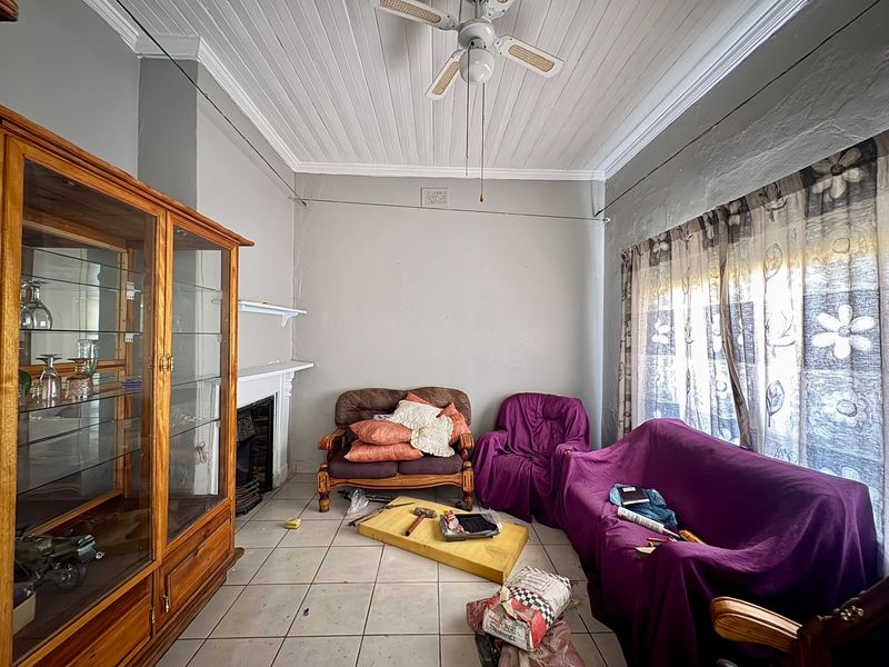 Living room featuring a fireplace with mantelpiece, tiled flooring, and a classic tongue and groove ceiling, offering potential for cosmetic updates.