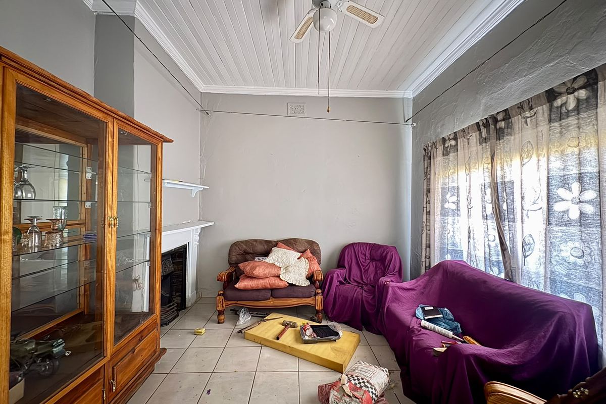 Living room featuring a fireplace with mantelpiece, tiled flooring, and a classic tongue and groove ceiling, offering potential for cosmetic updates.