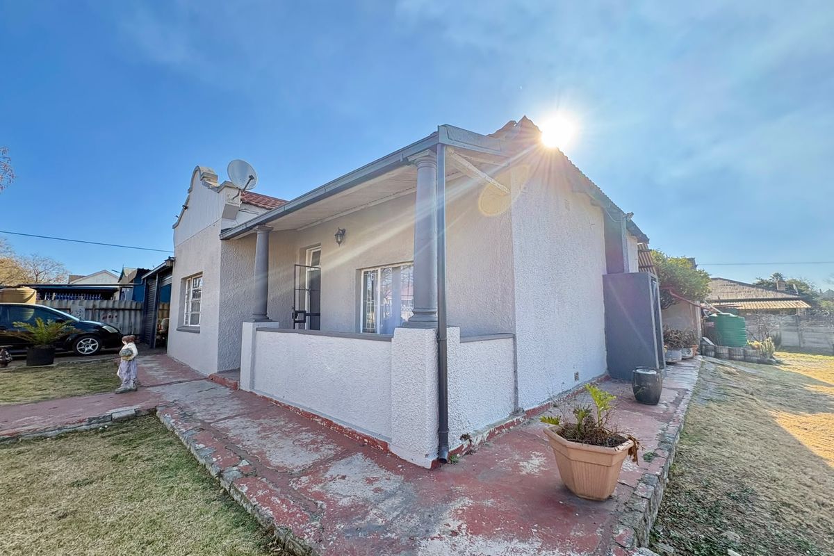 Rear view of the house featuring a covered patio area with concrete columns and a surrounding painted concrete walkway.