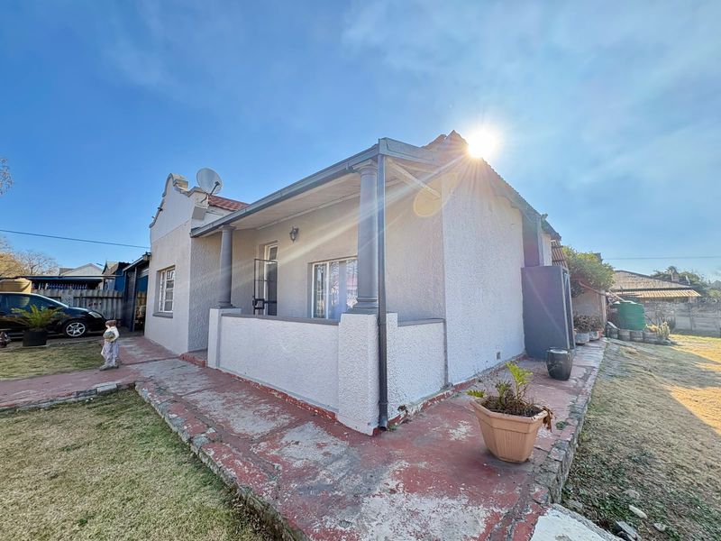 Rear view of the house featuring a covered patio area with concrete columns and a surrounding painted concrete walkway.