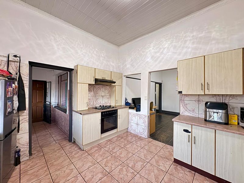 A functional kitchen featuring built-in cabinetry, gas hob, electric oven, and tiled flooring, offering a practical layout with potential for modern updates.