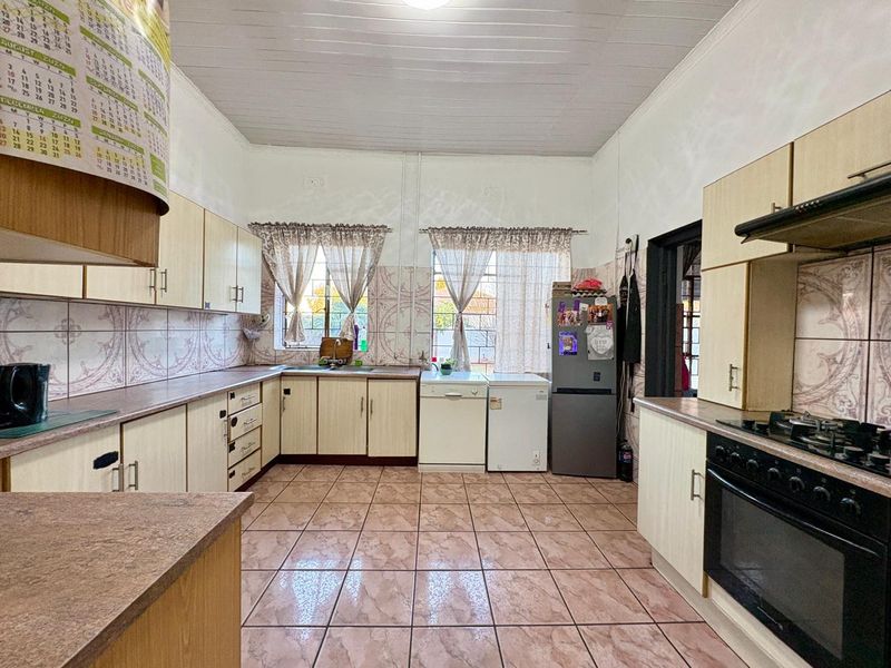 A functional kitchen featuring built-in cabinetry, tiled splashbacks, gas hob, and oven, with a classic layout and tiled flooring throughout.