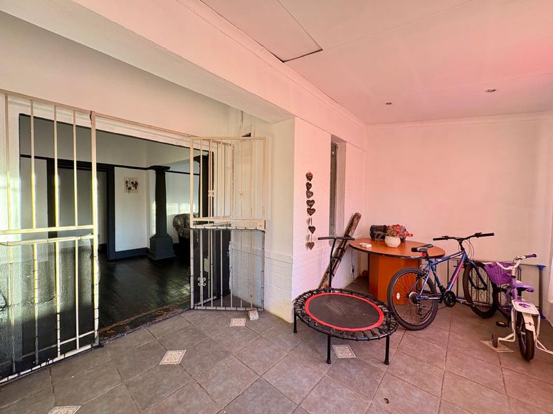 A covered patio area featuring tiled flooring and a security gate, providing a transition space between the outdoor area and the home interior.