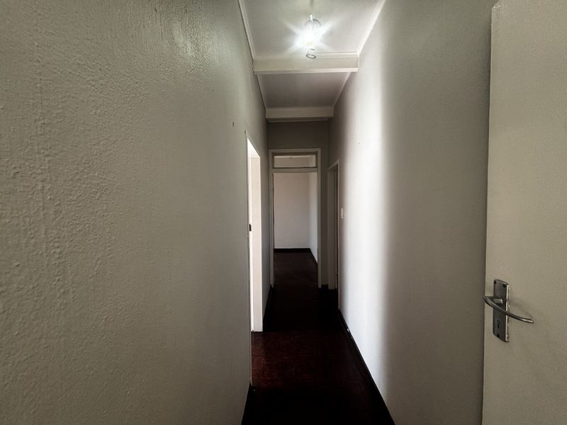 A functional interior hallway connecting multiple rooms, featuring neutral wall finishes, timber flooring, and standard internal door access.