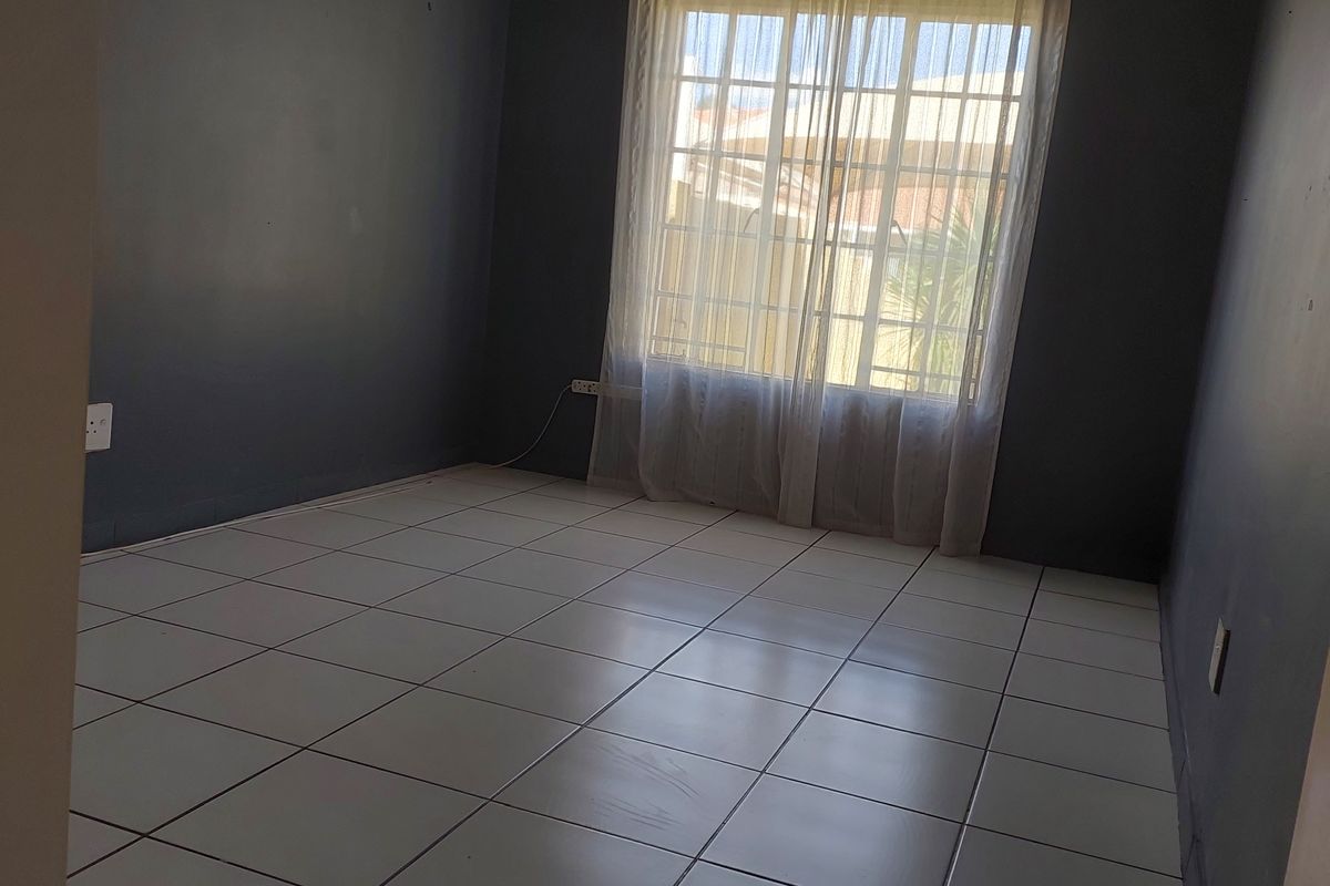 An empty bedroom featuring dark painted walls and neutral tiled flooring, providing a blank canvas for personalization.