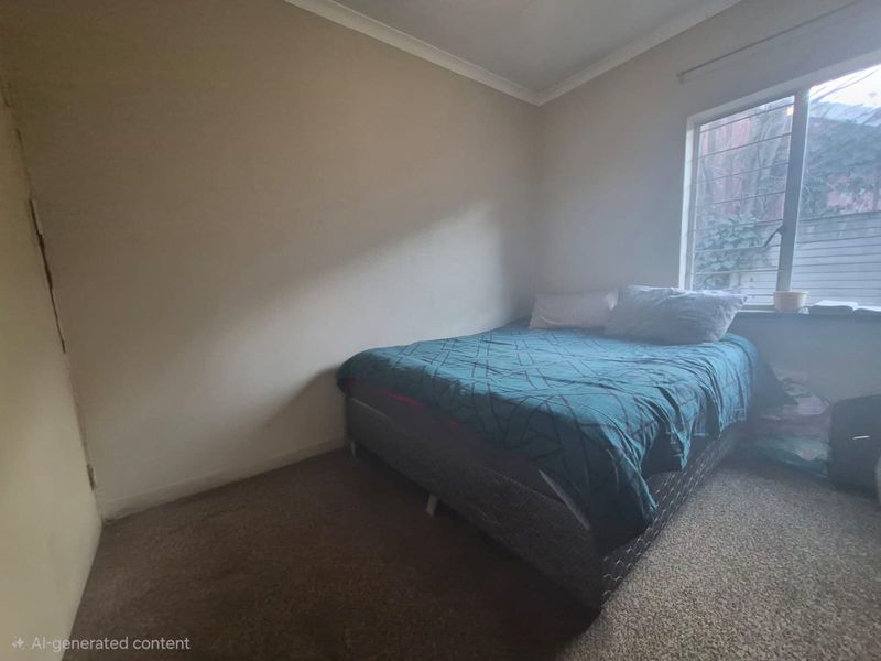 A simple bedroom featuring carpeted flooring, a window with security bars, and coved ceiling detailing.