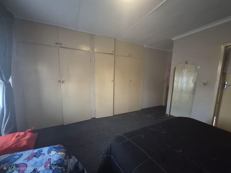 A bedroom featuring extensive built-in cupboard storage and coved ceiling detailing, requiring cosmetic updates to modernize the space.