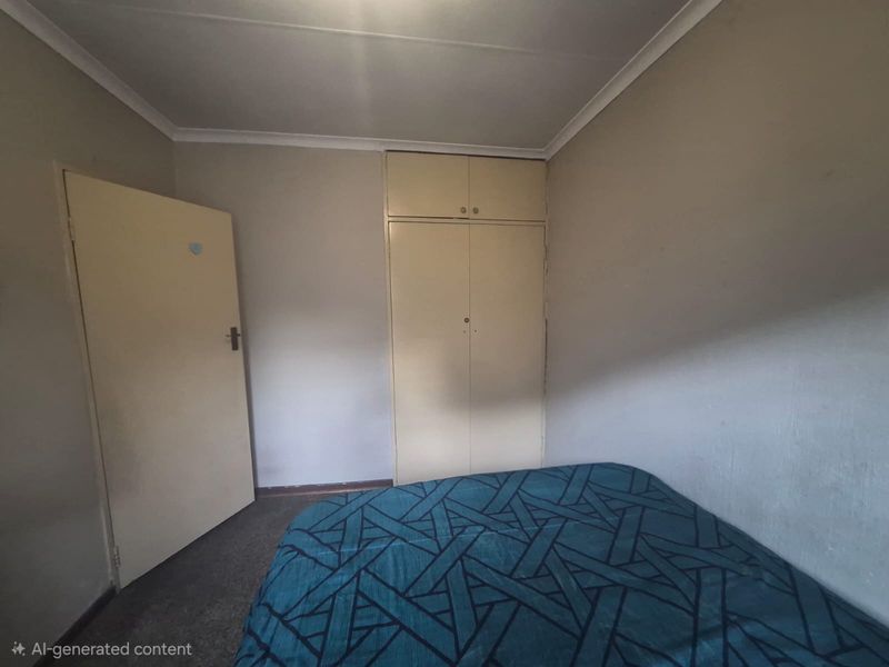A compact bedroom featuring built-in cupboards and coved ceiling detailing, requiring cosmetic updates to improve the overall aesthetic.
