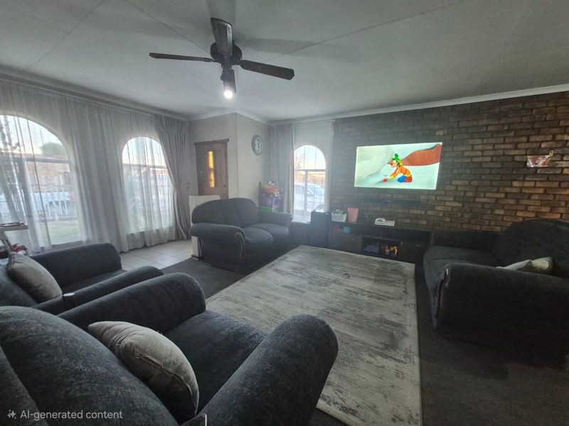 A living room featuring an exposed brick feature wall, arched windows with curtains, and a ceiling fan.