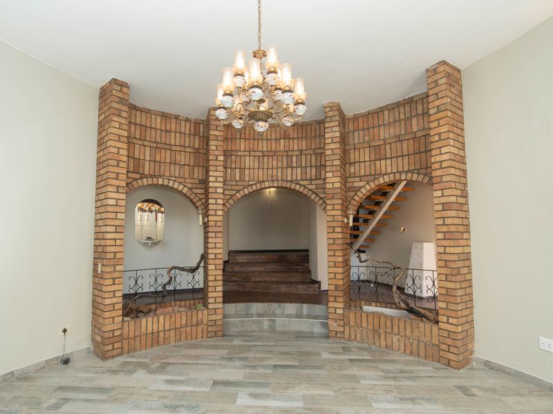 Spacious entrance hall featuring distinctive brick archways, a central staircase, and decorative wrought iron detailing, creating a unique architectural focal point.