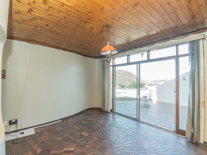 An empty living room featuring a timber-clad ceiling, brick flooring, and large sliding glass doors that open onto an outdoor patio area.