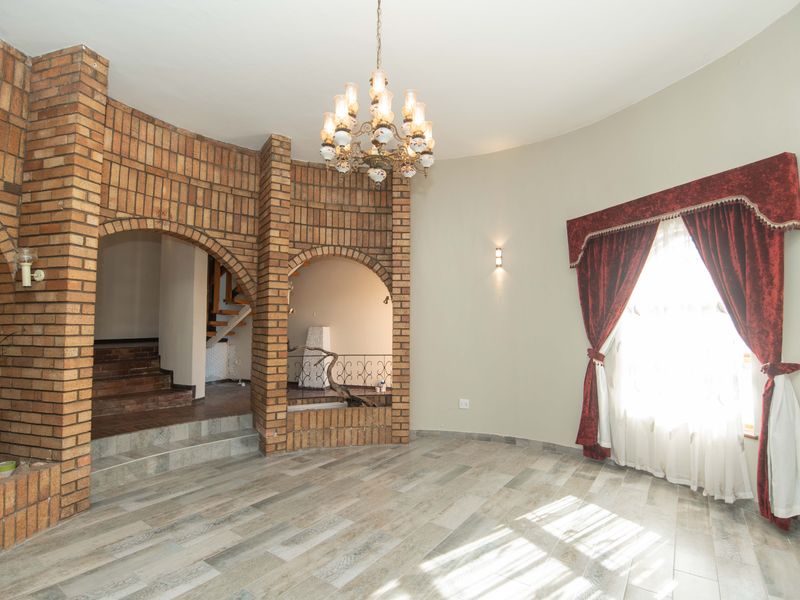Spacious living area featuring distinctive brick archways, tiled flooring, and a classic chandelier, offering a unique architectural character.