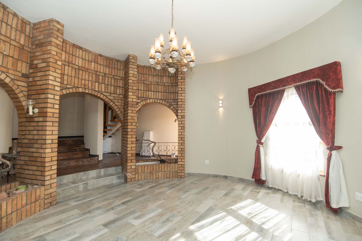 Spacious living area featuring distinctive brick archways, tiled flooring, and a classic chandelier, offering a unique architectural character.