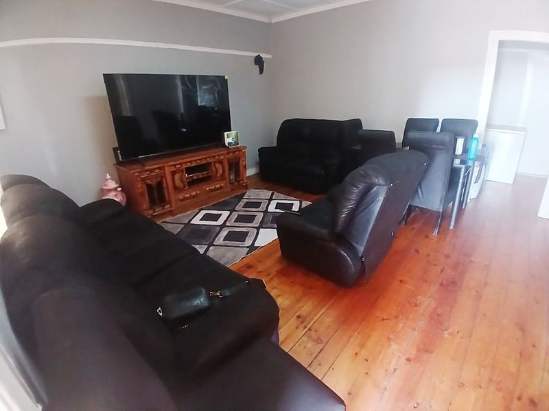 A living room featuring polished hardwood flooring and a traditional picture rail, providing a neutral base for interior design updates.