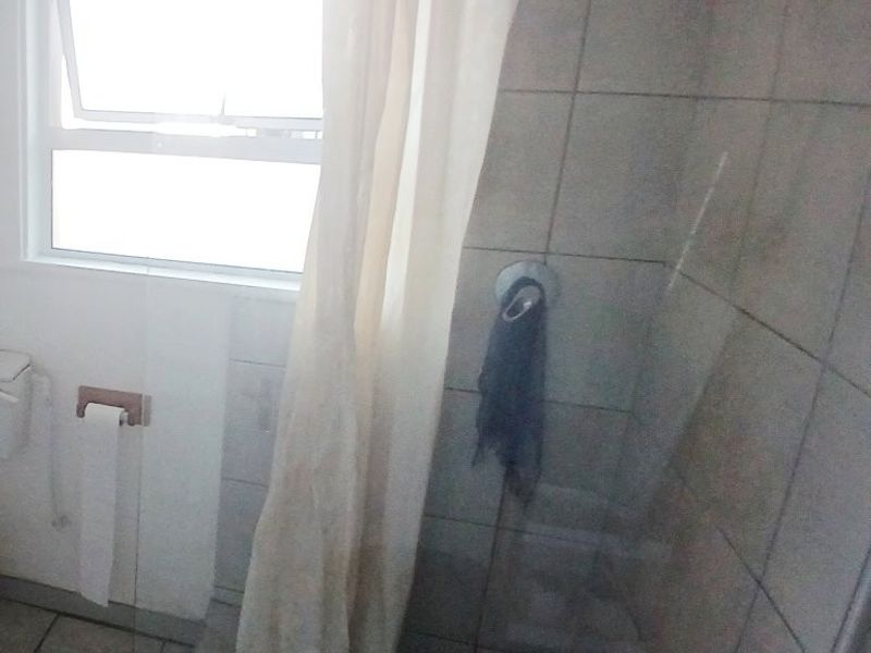 A functional bathroom featuring a shower area with tiled walls and flooring, including a window for natural light and ventilation.