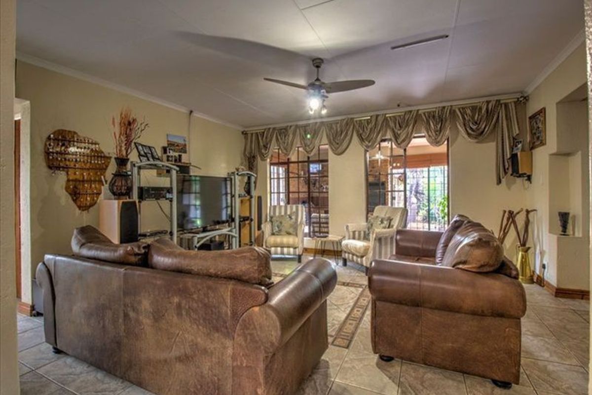 Spacious living room featuring tiled flooring, a ceiling fan, and large sliding glass doors providing natural light and access to the outdoor area.