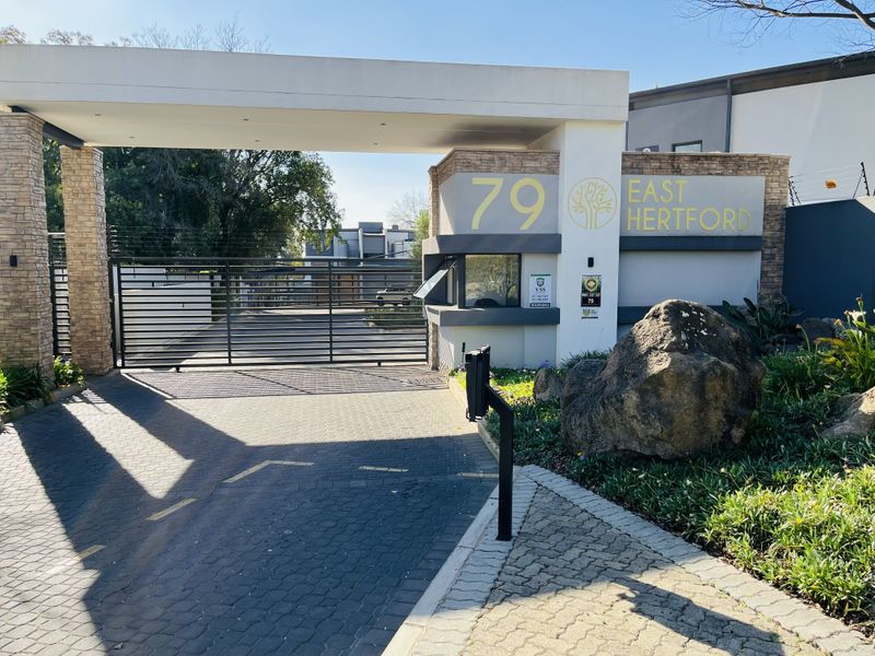 The secure entrance gate and guard house of the East Hertford apartment complex, featuring modern stone cladding and automated access control.