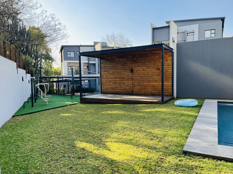 Outdoor pool area featuring a swimming pool, timber deck with a covered structure, and an artificial grass section.