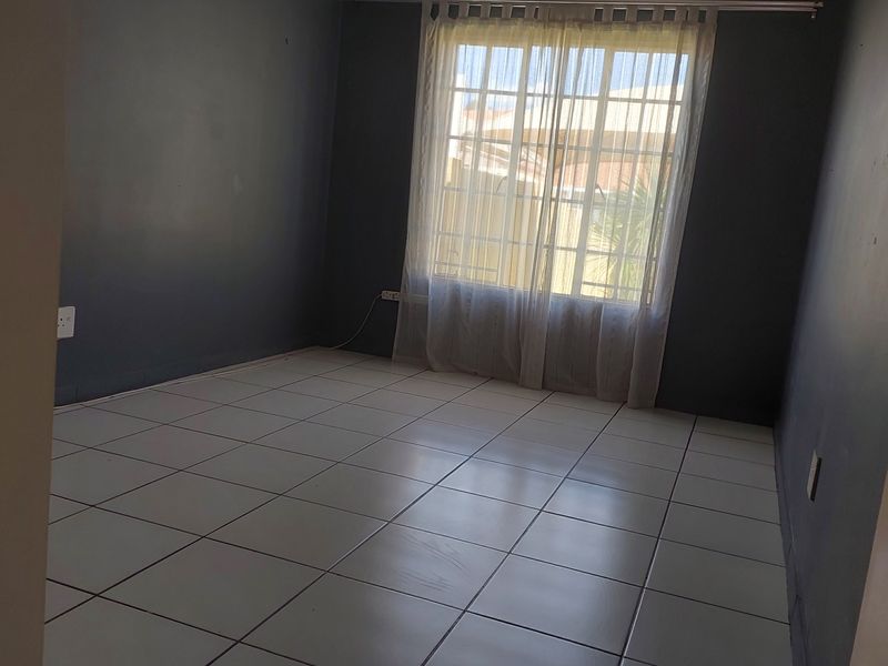An empty bedroom featuring dark painted walls and neutral tiled flooring, providing a blank canvas for personalization.