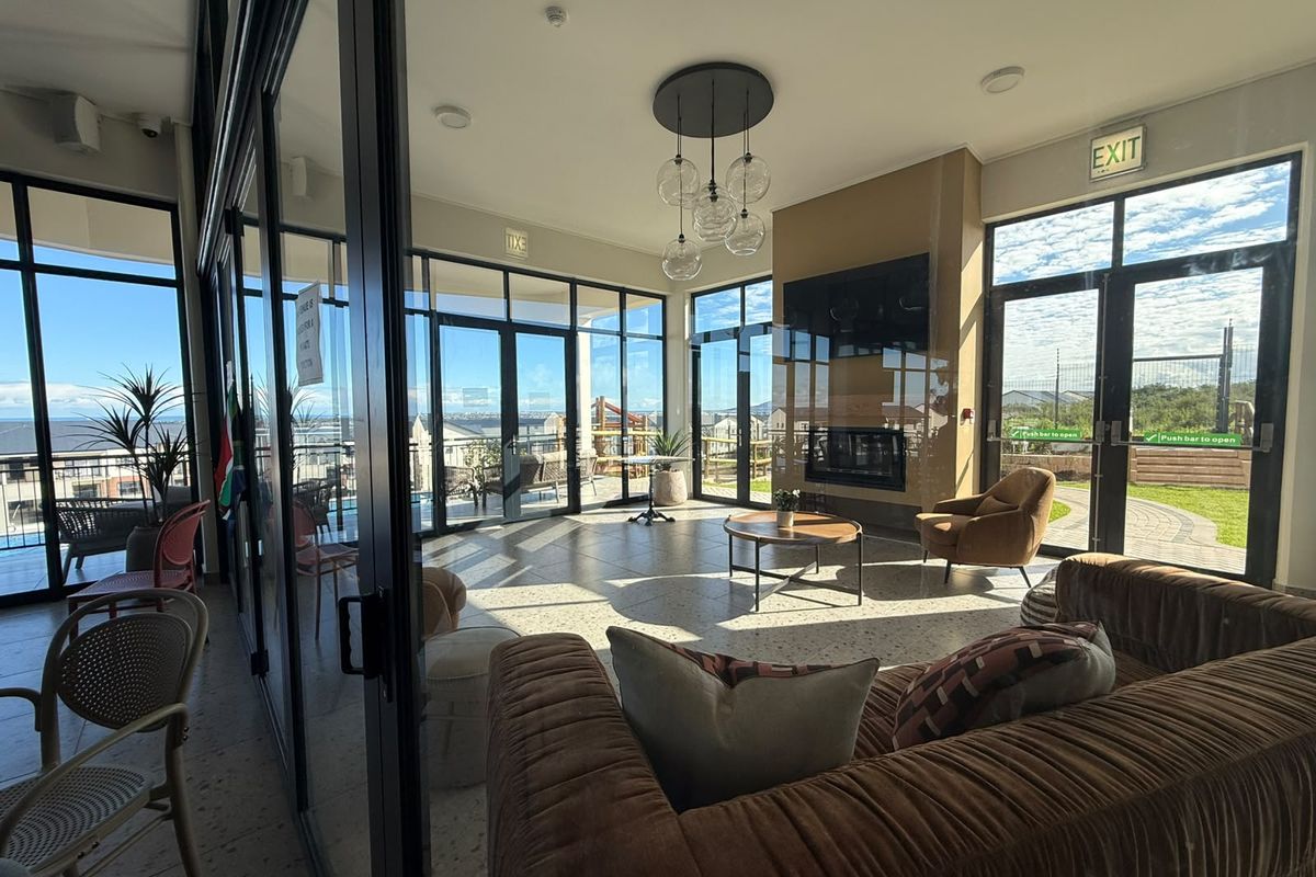 Modern, light-filled living area featuring expansive glass walls, terrazzo flooring, and a sleek built-in fireplace, offering seamless indoor-outdoor flow.