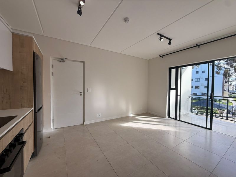 Modern open-plan living area featuring tiled floors, sleek built-in cabinetry, and large sliding glass doors leading to a private balcony.