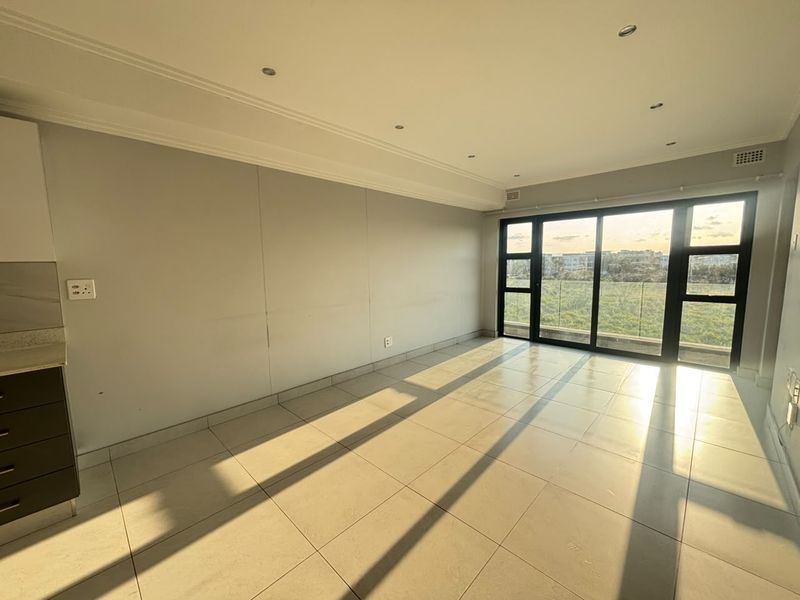 An open-plan living area featuring tiled floors, recessed lighting, and large sliding glass doors that provide natural light and access to the exterior.