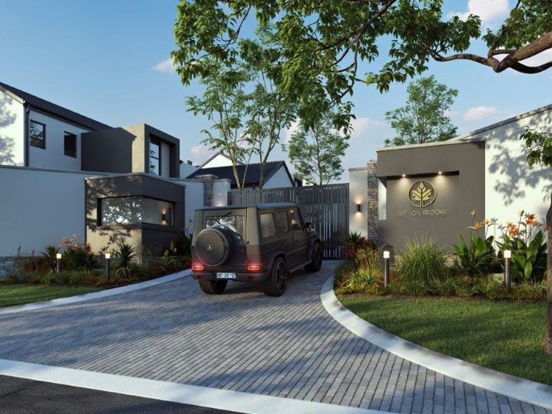 A modern residential cluster entrance featuring a paved driveway, secure gated access, stone accents, and contemporary architectural design.