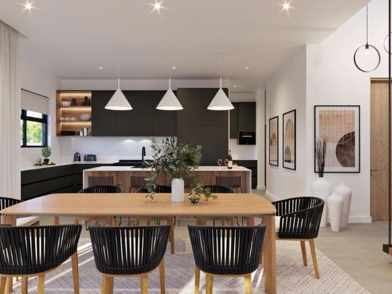 Modern open-plan living and dining area featuring a sleek kitchen with island, contemporary pendant lighting, and a stylish staircase with metal balustrades.