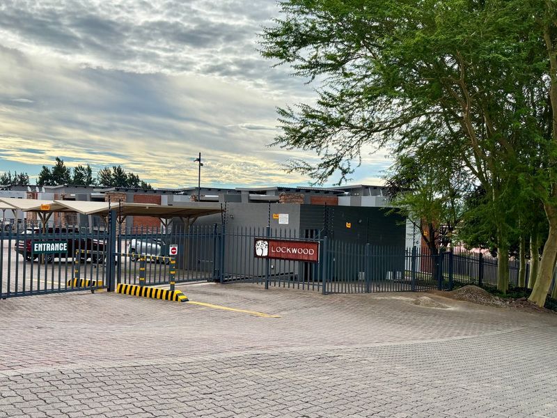 Front entrance view of the Lockwood apartment complex featuring secure gated access, paved driveway, and covered parking bays.