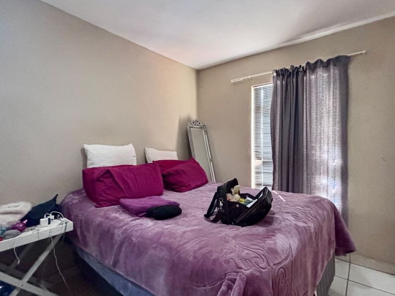 A standard bedroom featuring tiled flooring and window blinds, providing a functional space with neutral wall tones.