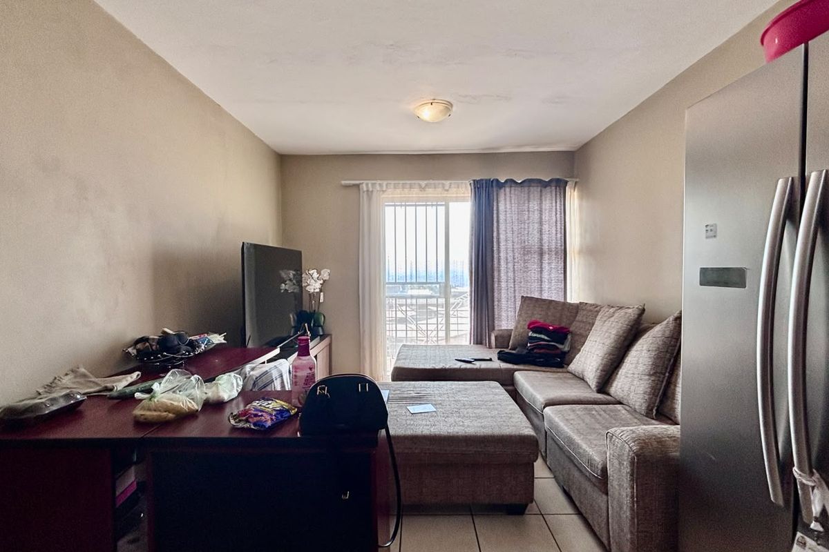 A living room area featuring tiled flooring and a sliding glass door with security gate leading to an outdoor space.