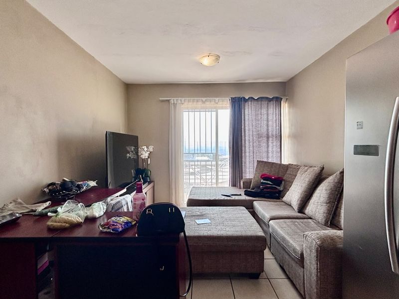 A living room area featuring tiled flooring and a sliding glass door with security gate leading to an outdoor space.