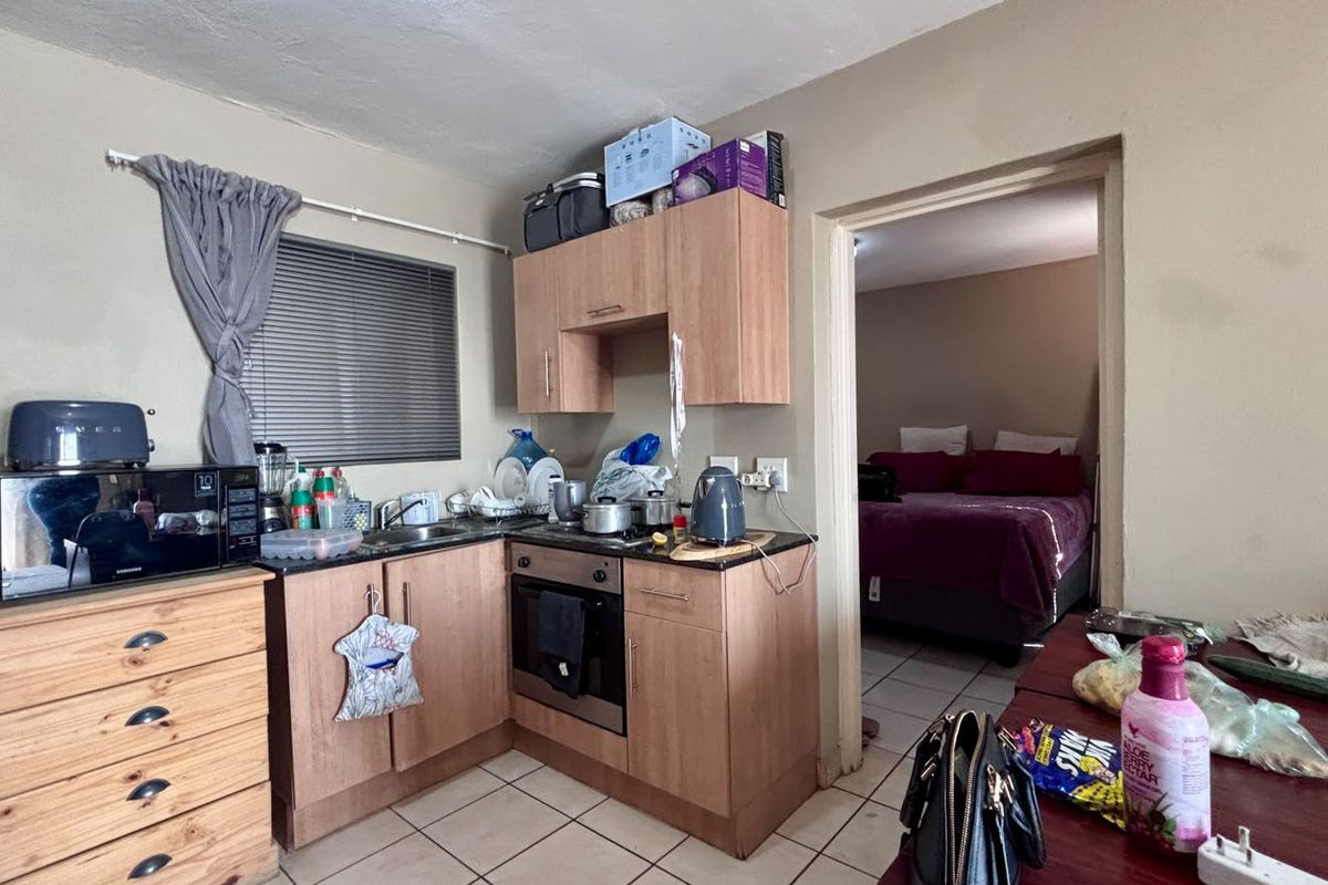Compact kitchen featuring built-in cabinetry, laminate countertops, and a stainless steel oven, with direct access to the adjacent bedroom.