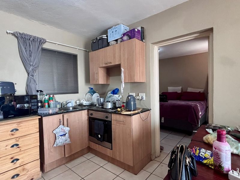 Compact kitchen featuring built-in cabinetry, laminate countertops, and a stainless steel oven, with direct access to the adjacent bedroom.