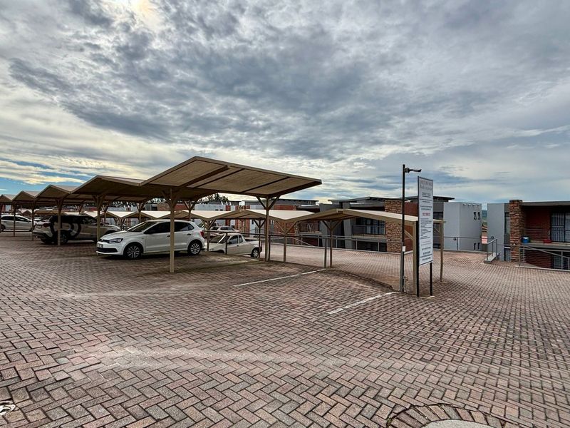 An outdoor paved parking area featuring multiple covered carport structures for resident vehicle storage.
