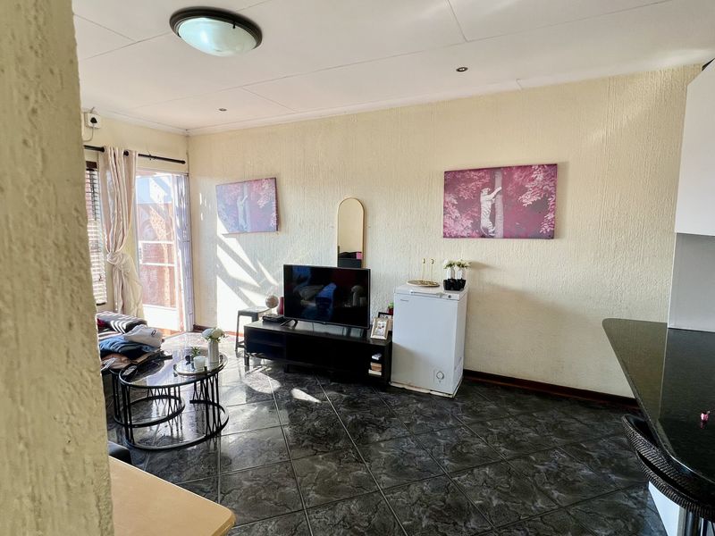 Open plan living area featuring dark tiled flooring, textured walls, and a sliding glass door providing access to the outdoor space.
