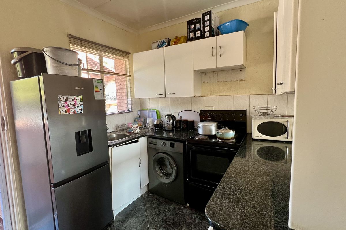 Compact kitchen featuring granite countertops, built-in cabinetry, tiled backsplash, and space for essential appliances, requiring some cosmetic updates to the wall finishes.