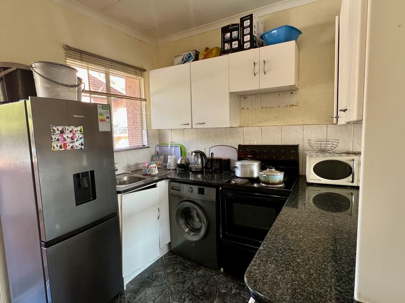 Compact kitchen featuring granite countertops, built-in cabinetry, tiled backsplash, and space for essential appliances, requiring some cosmetic updates to the wall finishes.