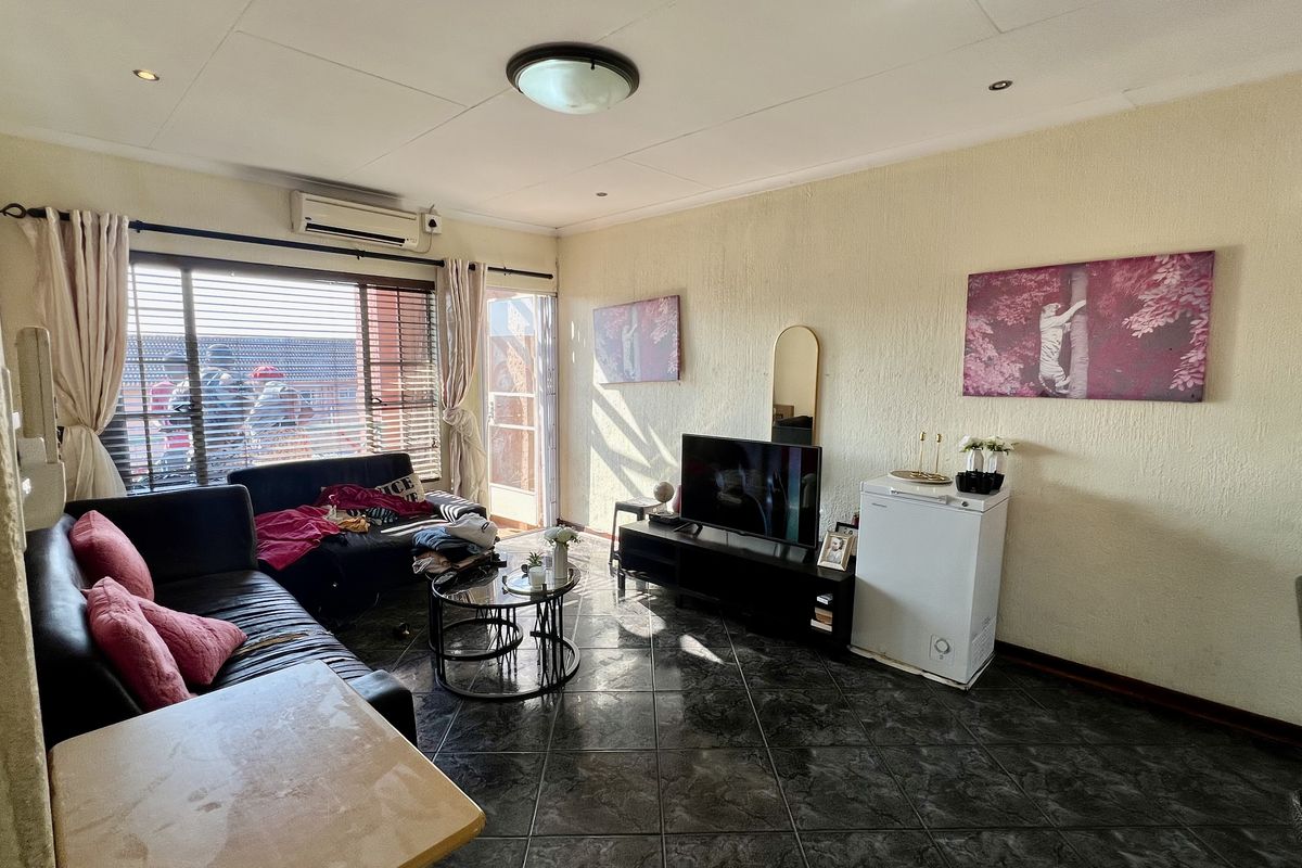 A living room featuring tiled flooring, recessed lighting, and an integrated air conditioning unit, with direct access to an outdoor area via a sliding door.