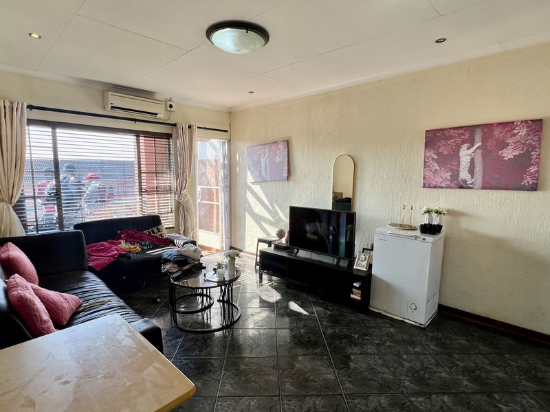 A living room featuring tiled flooring, recessed lighting, and an integrated air conditioning unit, with direct access to an outdoor area via a sliding door.