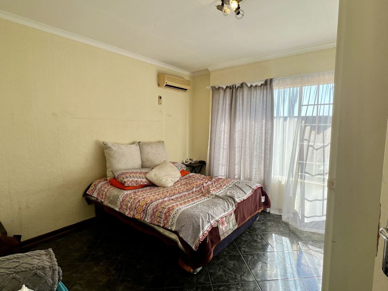 A bedroom featuring tiled flooring, an air conditioning unit, and a sliding glass door providing access to the exterior.